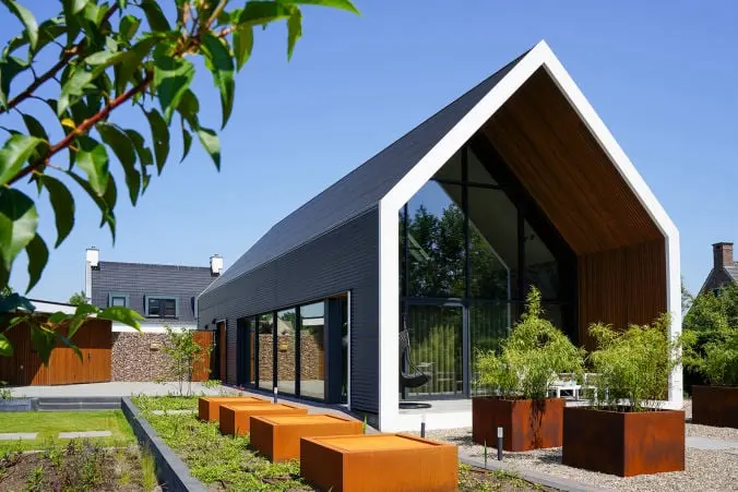 Foto van een moderne schuurwoning met grote glaspartijen, een zwart zadeldak dat doorloopt in de gevel.